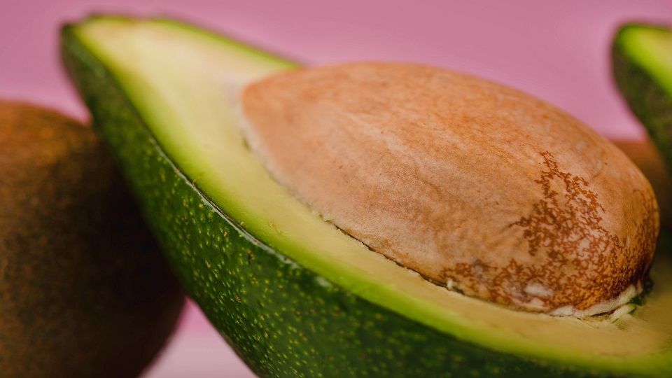 Close up picture of sliced ffresh avocado isolated on pink background
