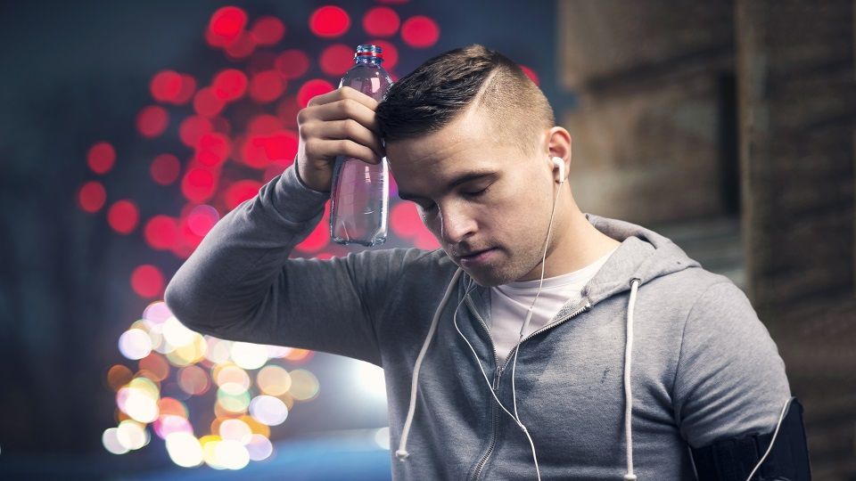 Young sportsman jogging in the night city with a water bottle