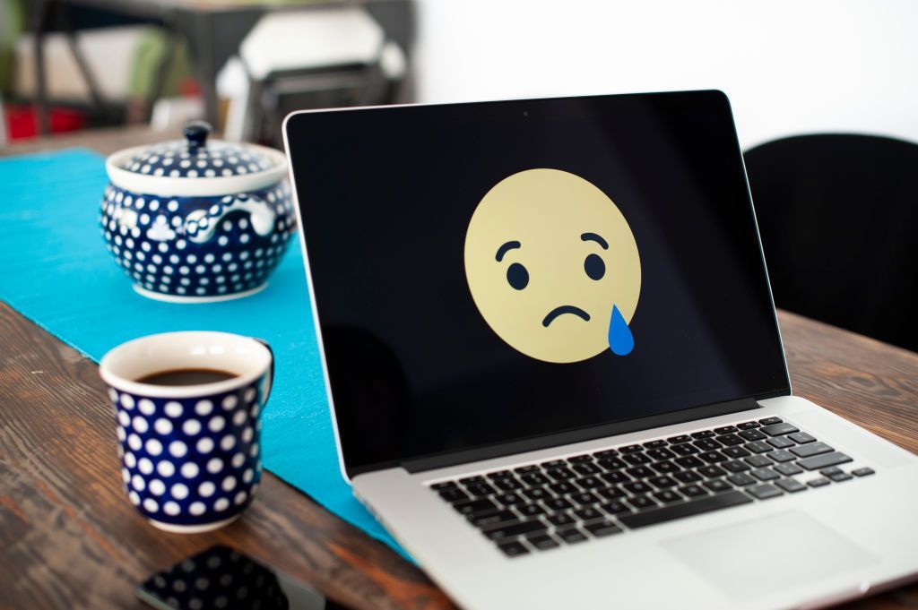 A laptop with a sad, crying emoji face is seen displayed in this photo illustration on October 15, 2018 in Warsaw, Poland. (Photo by Jaap Arriens/NurPhoto via Getty Images)
