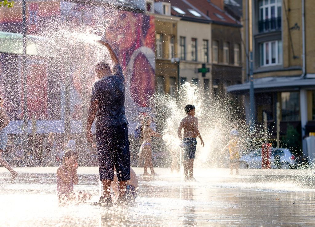 BRUSSELS, BELGIUM - JULY24: People cool off in the water of a fountain in Place Flagey, Brussels, Belgium on July 24, 2019.