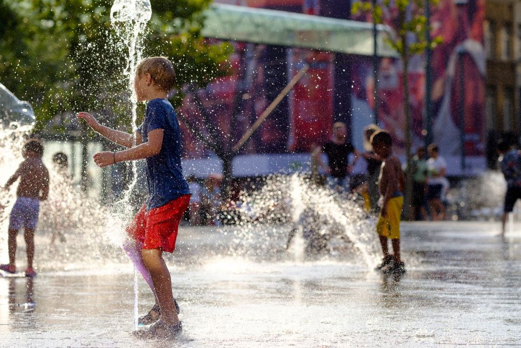 BRUSSELS, BELGIUM - JULY24: People cool off in the water of a fountain in Place Flagey, Brussels, Belgium on July 24, 2019.