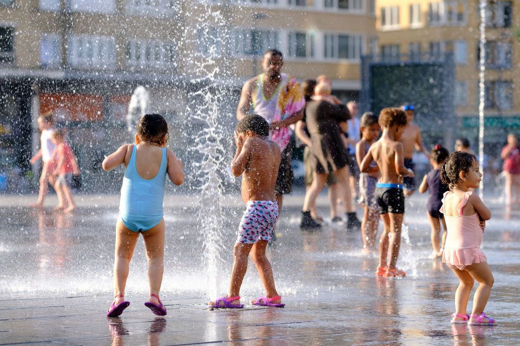 BRUSSELS, BELGIUM - JULY24: People cool off in the water of a fountain in Place Flagey, Brussels, Belgium on July 24, 2019.