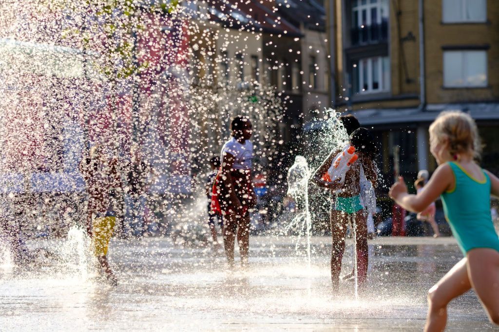 BRUSSELS, BELGIUM - JULY24: People cool off in the water of a fountain in Place Flagey, Brussels, Belgium on July 24, 2019.
