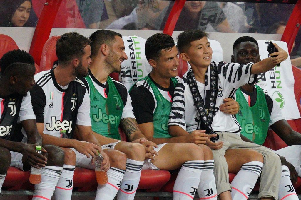 SINGAPORE, SINGAPORE - JULY 21: Cristiano Ronaldo of Juventus takes a selfie with a young fan at the substitute bench when the boy ran to him from across the field illegally during the International Champions Cup match between Juventus and Tottenham Hotspur at the Singapore National Stadium on July 21, 2019 in Singapore. (Photo by Allsport Co./Getty Images)