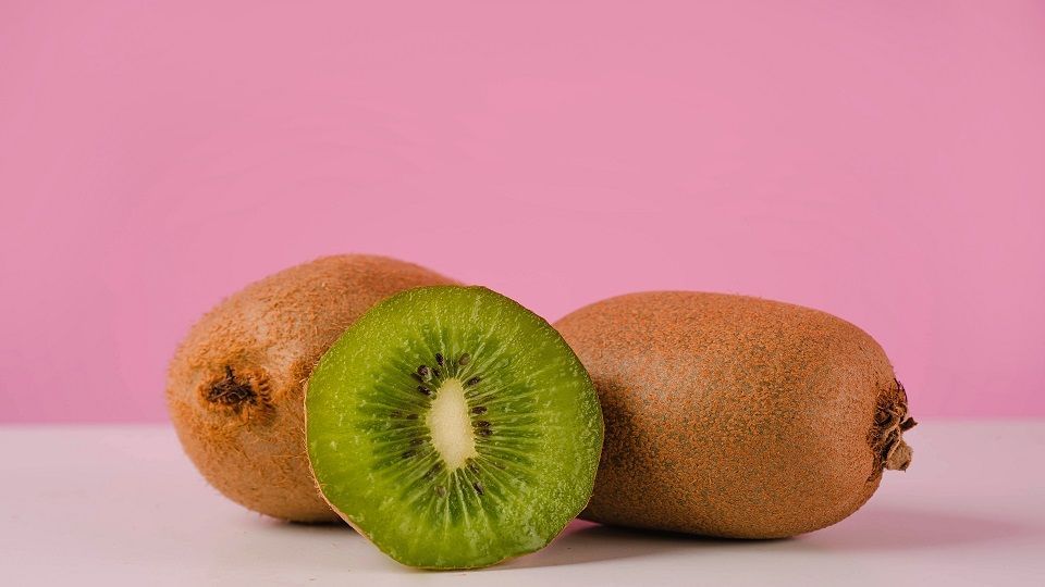 Fresh juicy sliced kiwi fruit on a table isolated on pink background