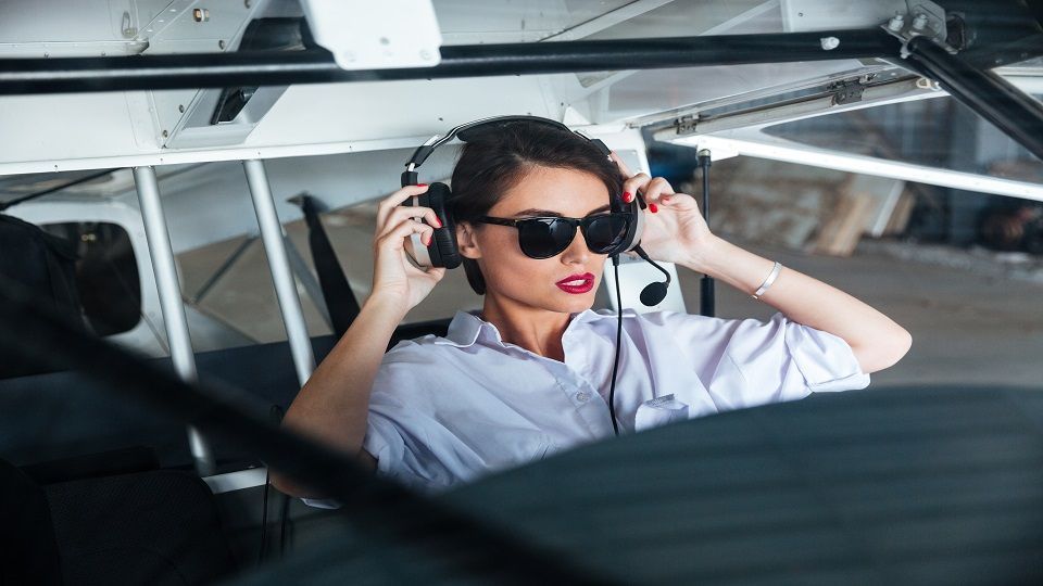 Pretty young woman pilot in headset ready to fly in small airplane