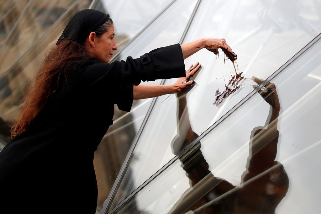 A Climate activist group 350.Org member puts her fake oil-covered hands on the glass Pyramid at the Louvre museum in Paris, France, September 27, 2019. The Climate activist group protests against the sponsor partnership between Total and the Louvre museum.  REUTERS/Charles Platiau