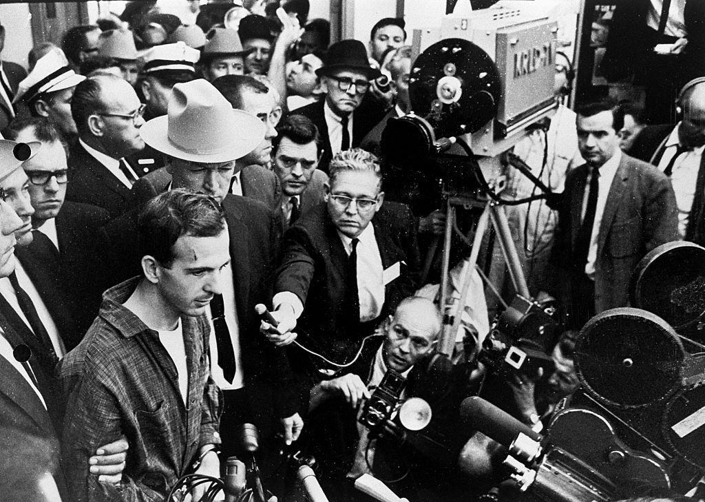 A television news conference captures guards and secret service agents escorting Lee Harvey Oswald at the Dallas police headquarters two days after his arrest in conjunction with the assassination of President Kennedy. Oswald was shot by local night club owner Jack Ruby shortly after this photograph was taken. (Photo by © CORBIS/Corbis via Getty Images)