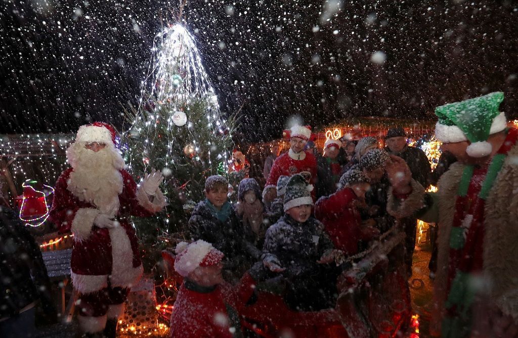 Serge Hennebel, nicknamed "Elf Serge", and a man dressed as Santa Claus (Father Christmas) interact with children in a hut in Hennebel's garden, which has been transformed into a Christmas village and adorned with hundreds of lights, in Hamme-Mille, Belgium December 7, 2019  REUTERS/Yves Herman