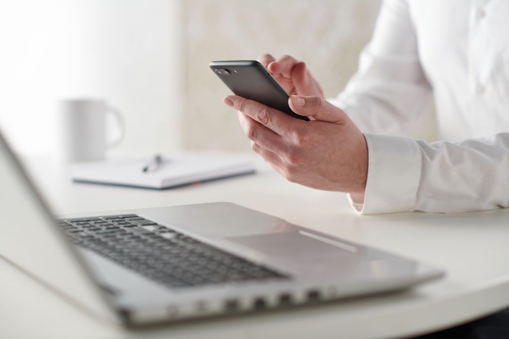 Close up detail of a businessman working at a desk with a smartphone and laptop computer, taken on January 31, 2019. (Photo by Neil Godwin/Future via Getty Images)