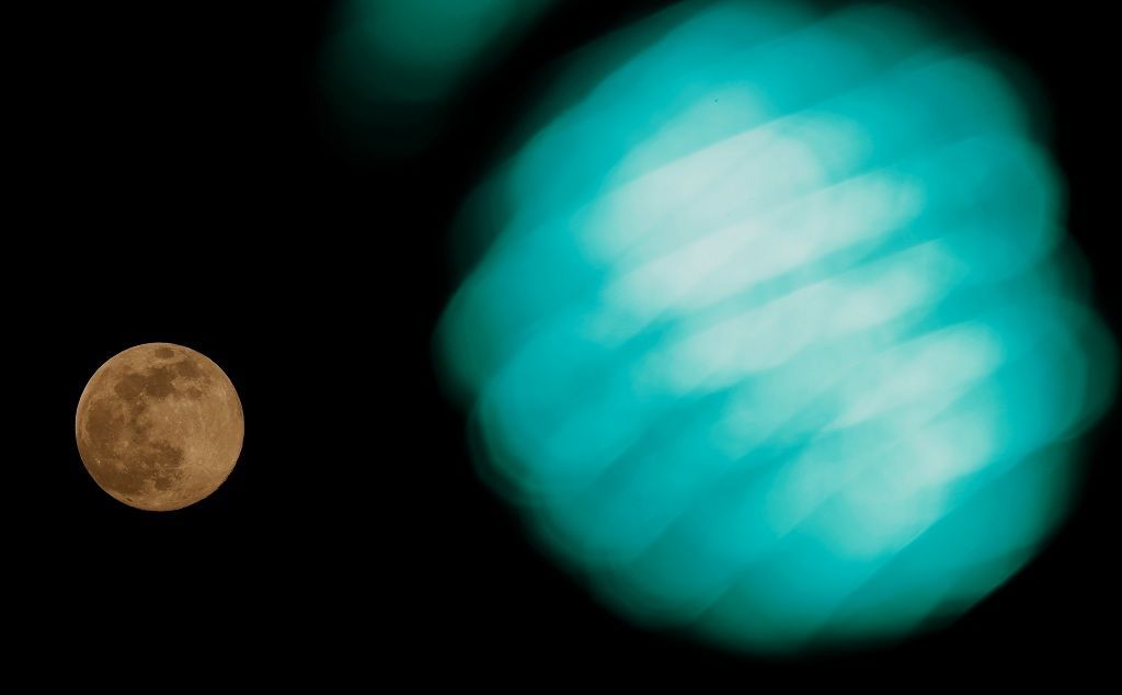 The Pink Supermoon rises by a traffic light in an astronomical event, that occurs when the moon is closest to the Earth in its orbit, making it appear much larger and brighter than usual, in Vienna, Austria April 7, 2020.   REUTERS/Leonhard Foeger