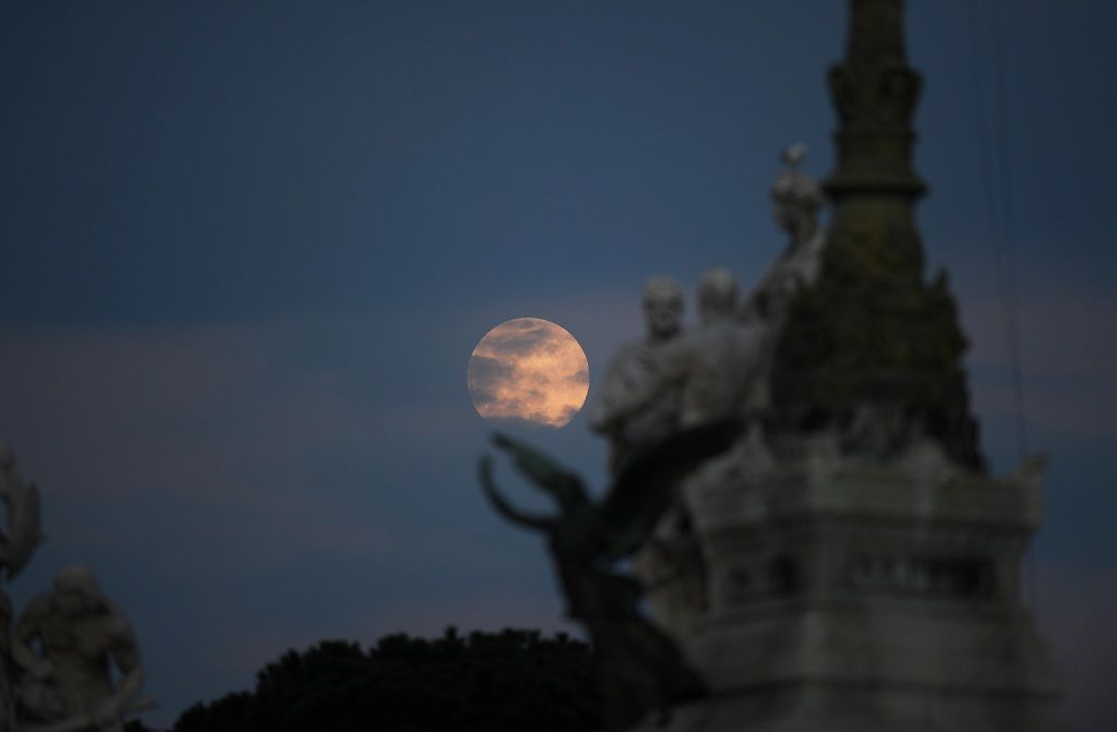 The pink supermoon rises over the city of Rome in an astronomical event that occurs when the moon is closest to the Earth in its orbit, making it appear much larger and brighter than usual, in Rome, Italy, April 7, 2020. REUTERS/Alberto Lingria