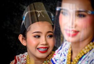 Traditional Thai dancers wearing protective face shields relax after a performance at the Erawan Shrine, which was reopened after the Thai government relaxed measures to combat the spread of the COVID-19 novel coronavirus, in Bangkok on May 4, 2020. - Thailand began easing restrictions related to the COVID-19 novel coronavirus on May 3 by allowing various businesses to reopen, but warned that the stricter measures would be re-imposed should cases increase again. (Photo by Mladen ANTONOV / AFP)