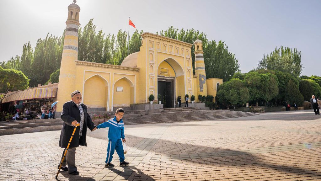 KASHGAR, CHINA - 2019/04/19: An elderly Uyghur man walks with a child with school uniform on in front of the Id Kah Mosque in Kashgar.The Xinjiang province is located in the North Western part of China, it is the largest province in China. Majority of the population are Muslim in Xinjiang. Recently the Chinese government has enforced a massive security crackdown in Xinjiang, where more than one million ethnic Uyghurs and other mostly Muslim minorities are believed to be held in a network of internment camps that Beijing describes as "vocational education centres" aimed at steering people away from religious extremism. (Photo by Geovien So/SOPA Images/LightRocket via Getty Images)