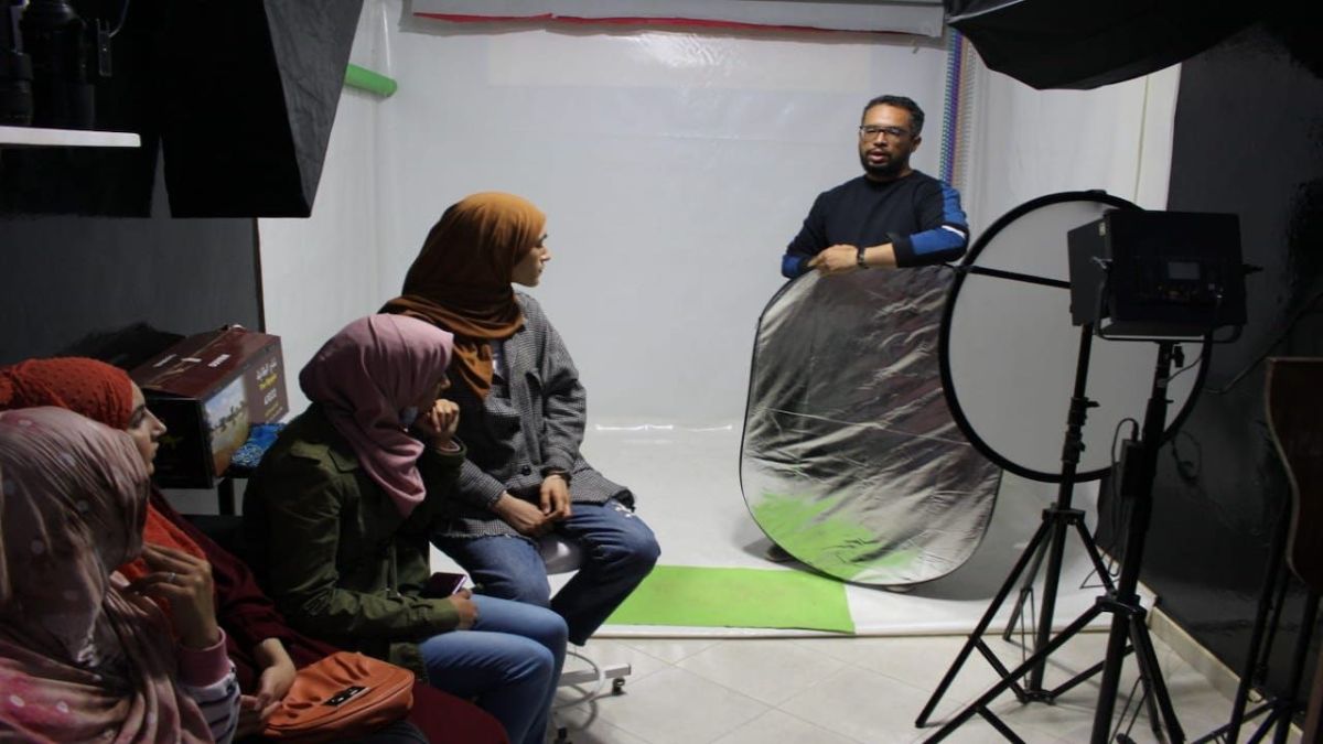 مدرب التصوير يشرح عن الإضاءة لعدد من المتدربين 