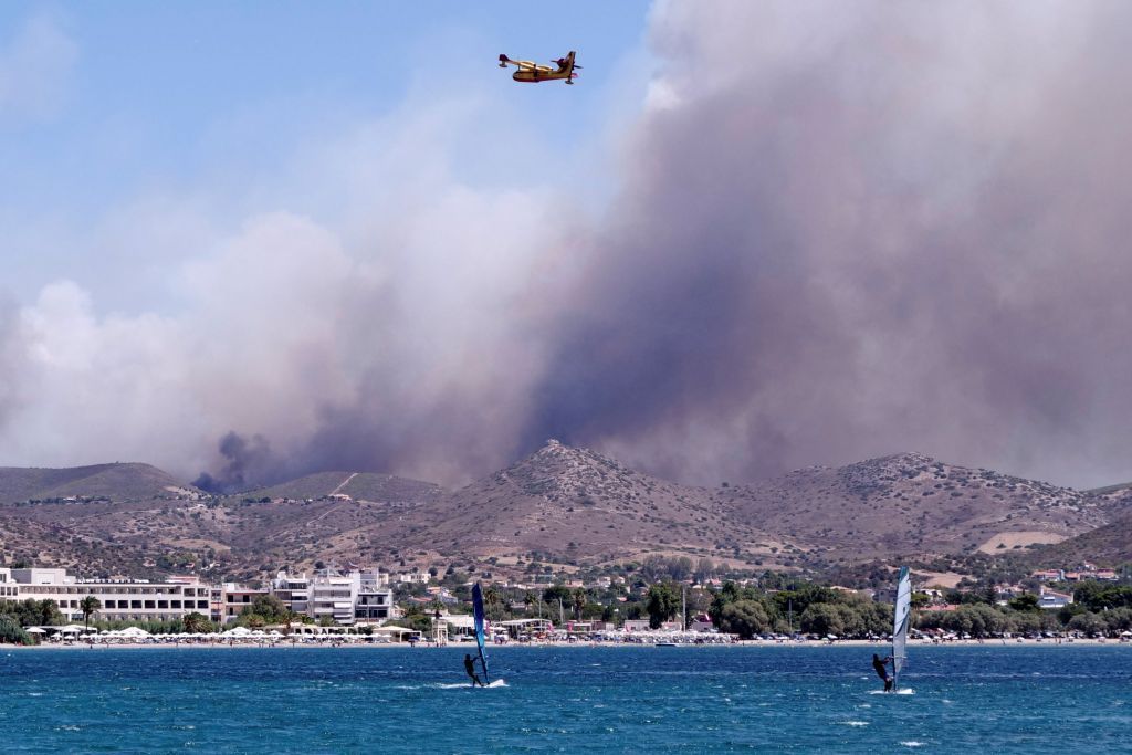 People windsurf as a wildfire burns near the village of Markati as seen from the village of Nea Fokaia, Greece, August 16, 2021. REUTERS/Vassilis Triandafyllou